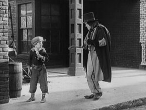 Scene from silent film Dr. Pyckle and Mr. Pryde. Pryde (Stan Laurel) is menacingly approaching a boy with an ice cream cone.